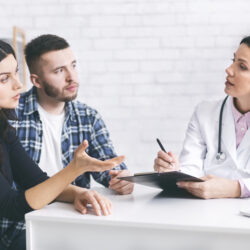 attentive couple listening to their doctor about having a safe pregnancy during the COVID-19 pandemic | Reproductive Science Center of the SF Bay Area