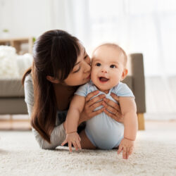 Mother kissing little baby at home