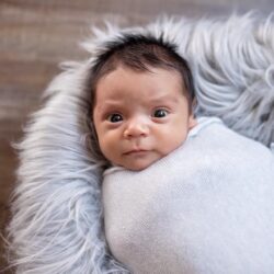 Baby Robert Joseph Ramirez swaddled in white and looking intensely at the camera | RSC of SF Bay Area