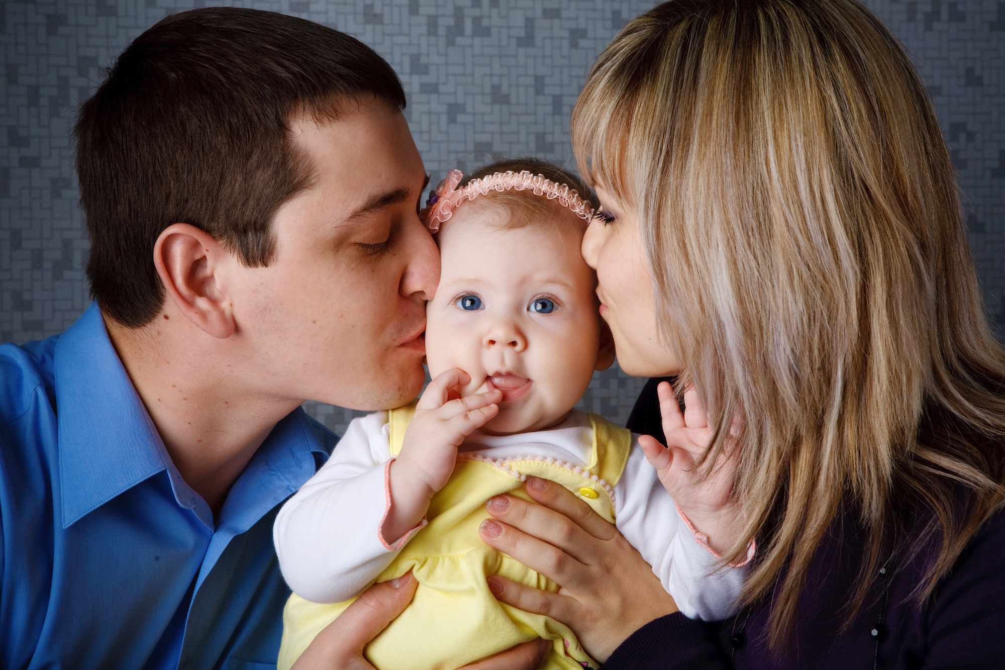 Spanish couple kissing cheeks of baby they conceived through IVF | Los Expertos en Fertilidad desde hace casi 30 años en el área de la bahía | RSC Bay Area